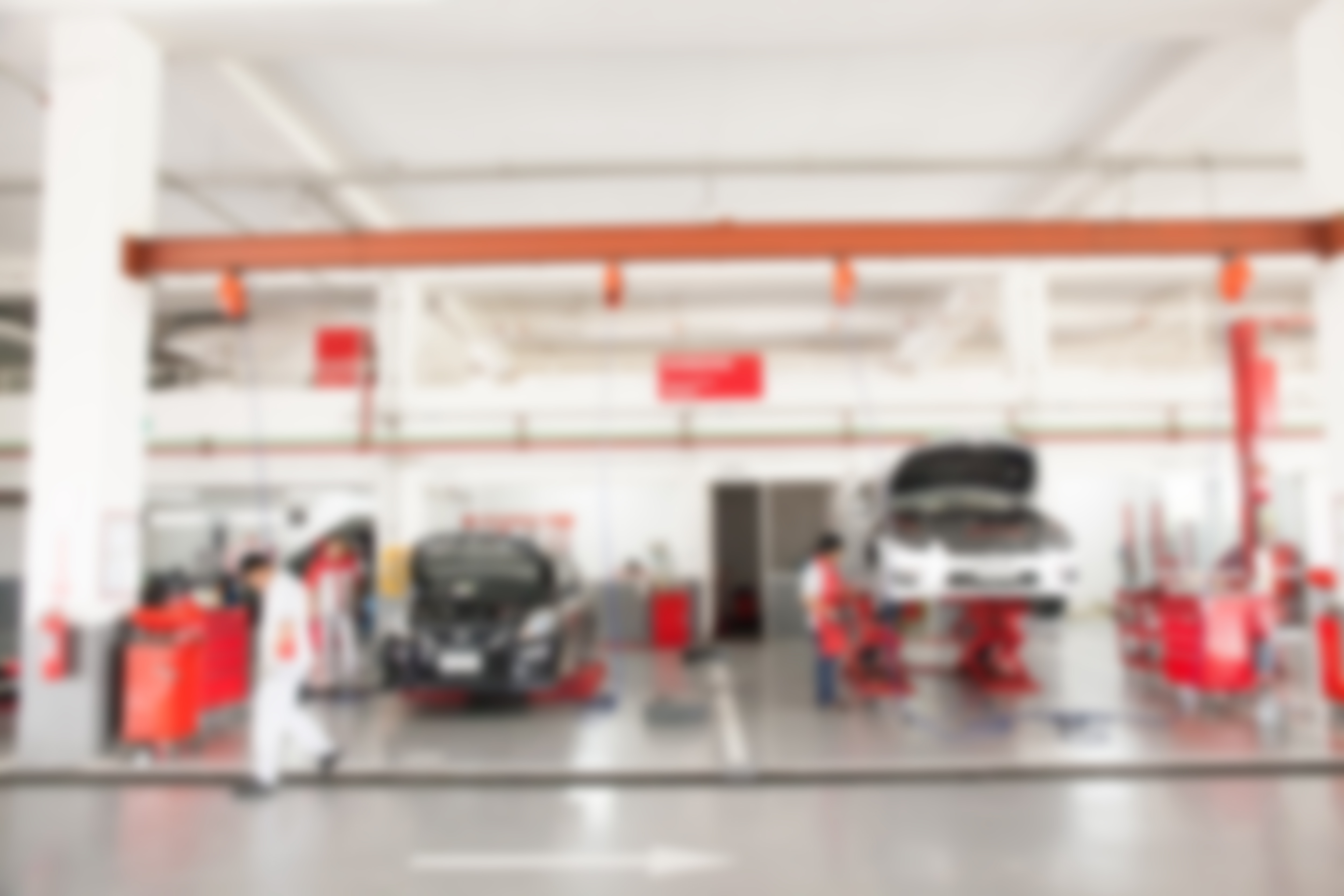 Blurred of inside car garage with cars being under maintenance and technicians for background